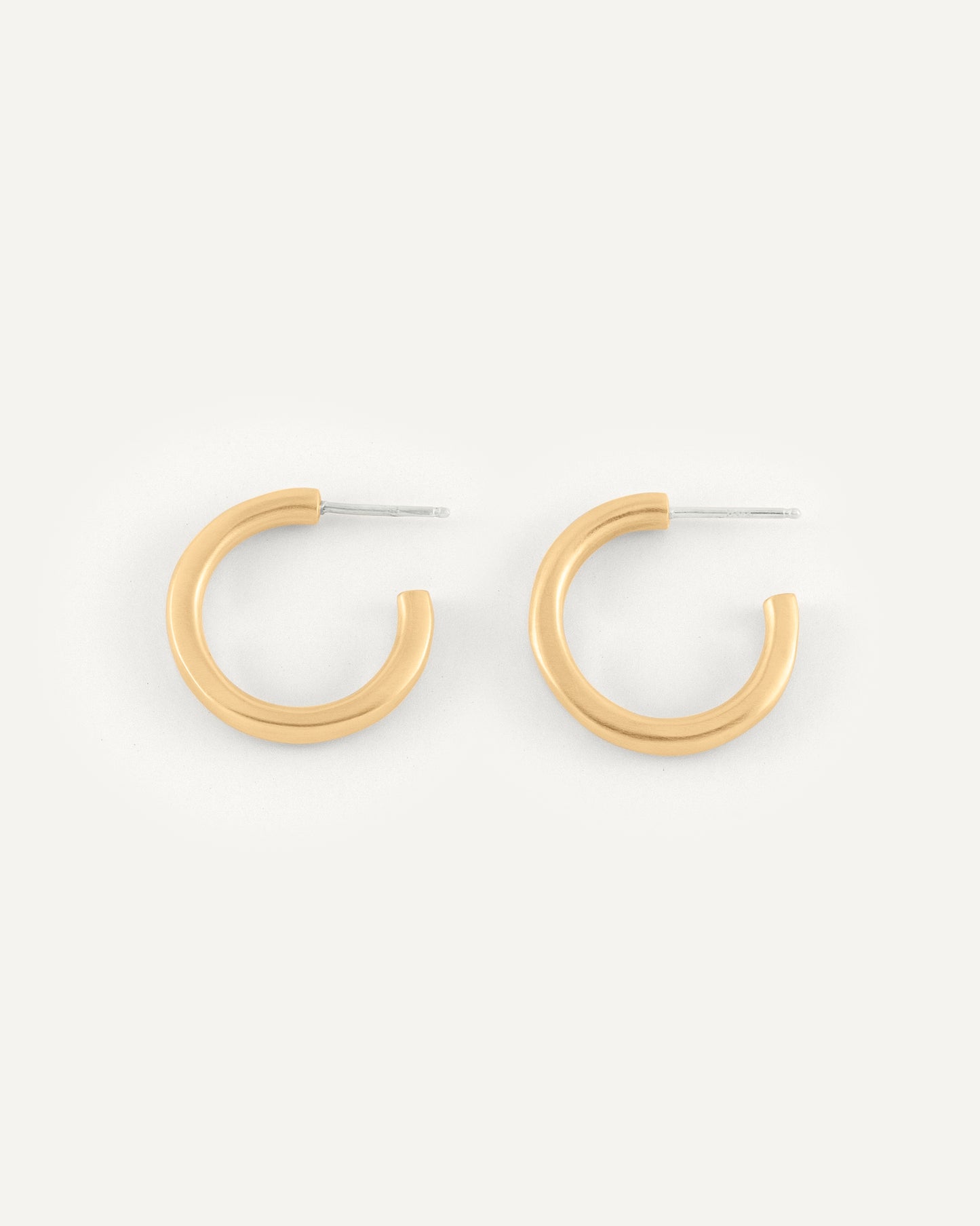 A pair of organic and fluid shape brass hoops in soft satin finish.