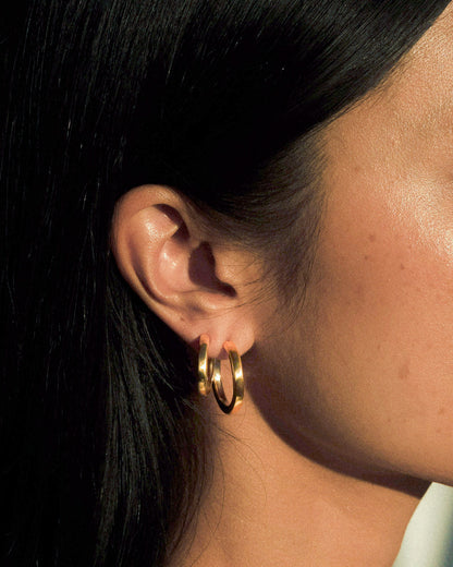 A model wearing small and large pair  of organic textured and fluid formed brass hoops.