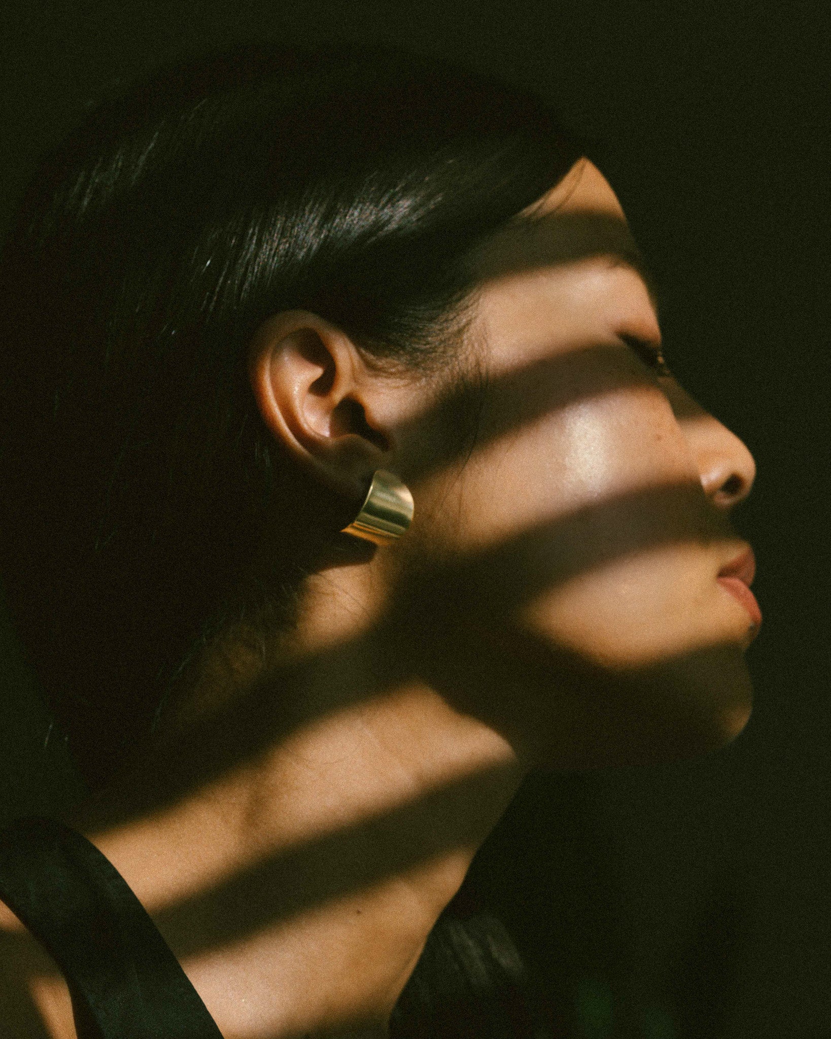 A model wearing a pair of curved and oval pebble-shaped earrings.