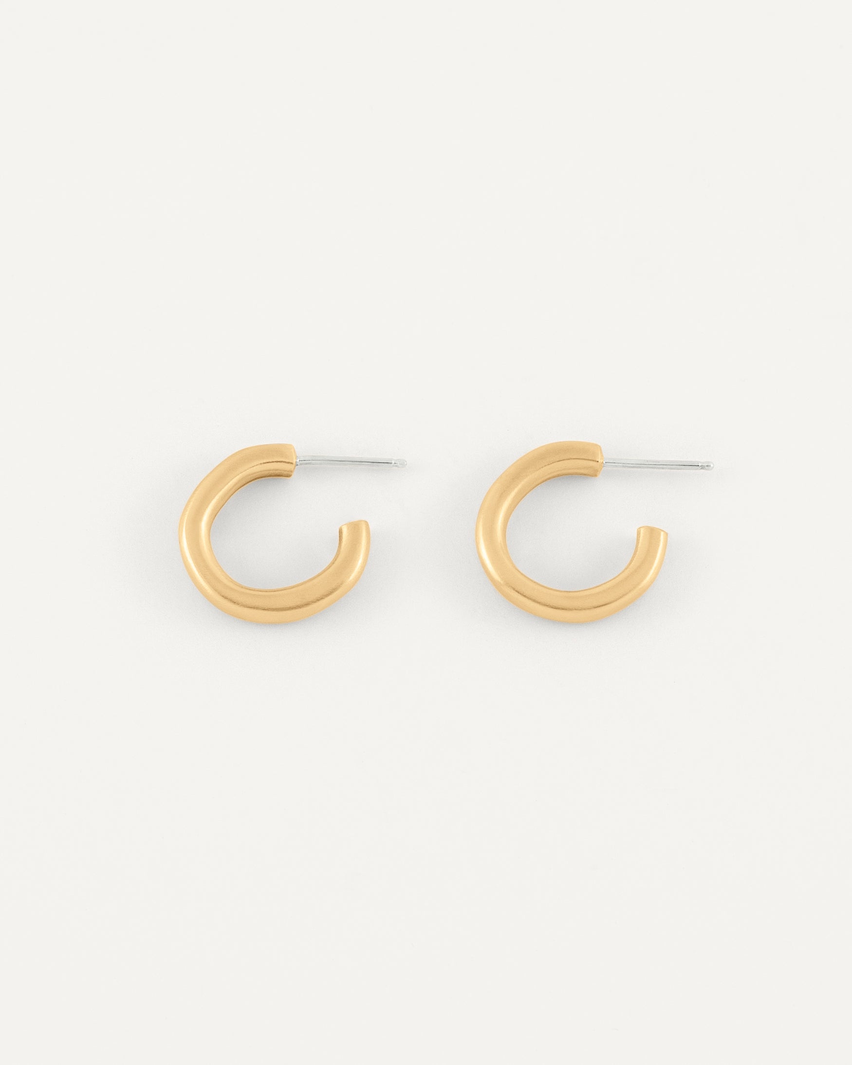 A pair of organic textured and fluid formed brass hoops in soft satin finish.