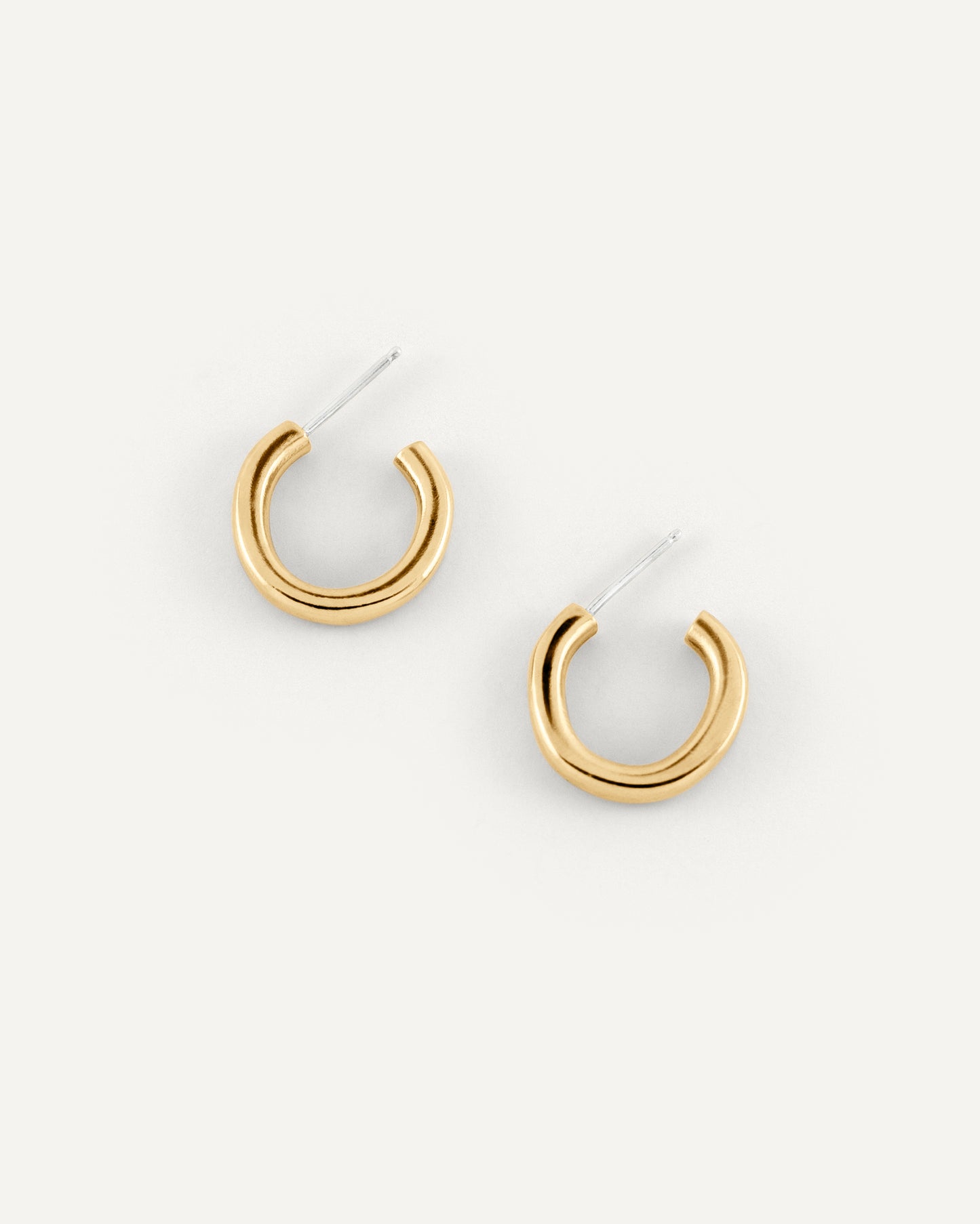 A pair of organic textured and fluid formed brass hoops in high polished finish